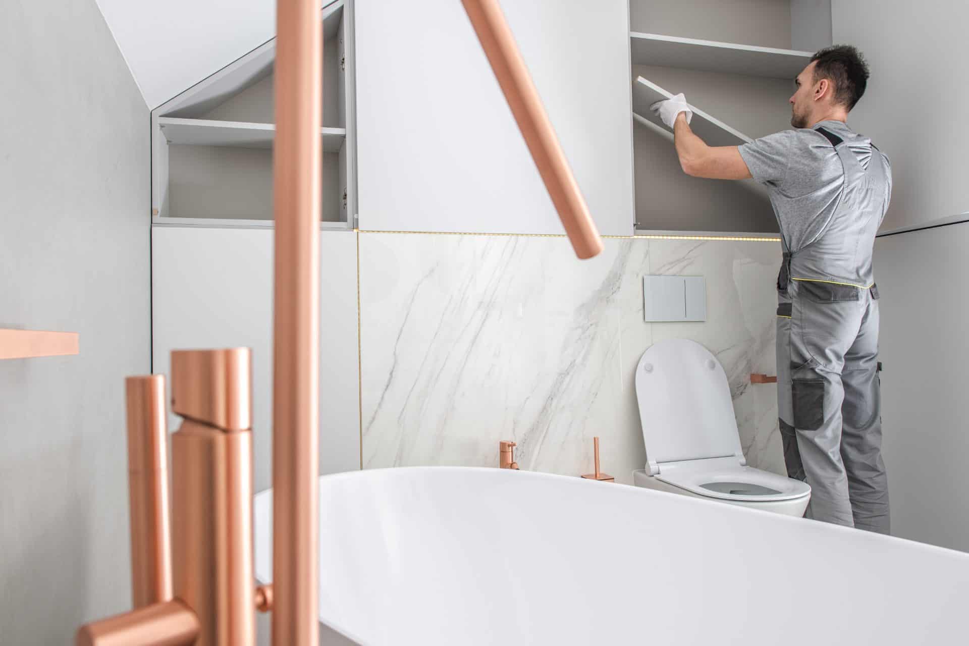 Bathroom Storage Building by Caucasian Home Improvement Worker. Elegant Modern Bathroom Interior. Bathroom Storage Building:bathroom,shelf,installing,furniture,custom,armoire,storage,drawer,wardrobe,cabinet,interior,inside,apartment,housing,home,elegant,white,empty,installation,organizer,assemble,modular,object,household.men,worker,installer,caucasian,bathtub,toilet