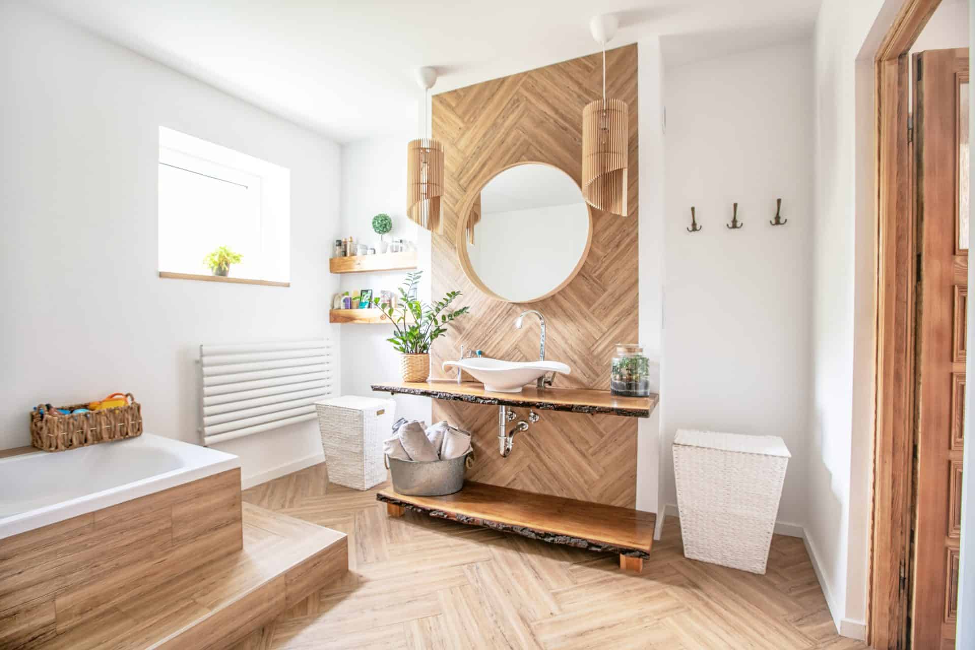 White sink on wood counter with a round mirror hanging above it. Bathroom interior.